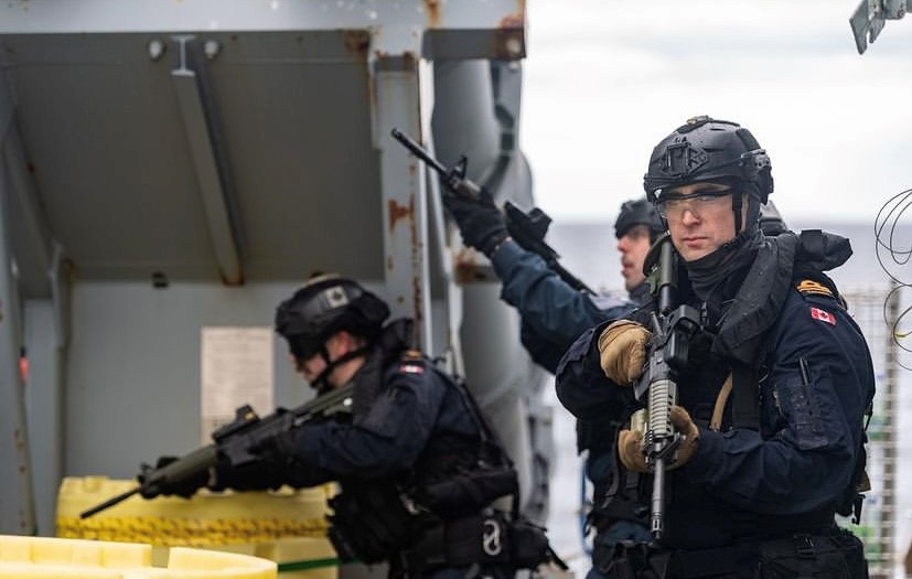 Three armed tactical officers in black gear aiming rifles during an operation.