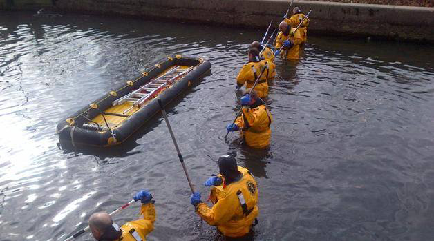 People in yellow life jackets paddling an inflatable raft on water.