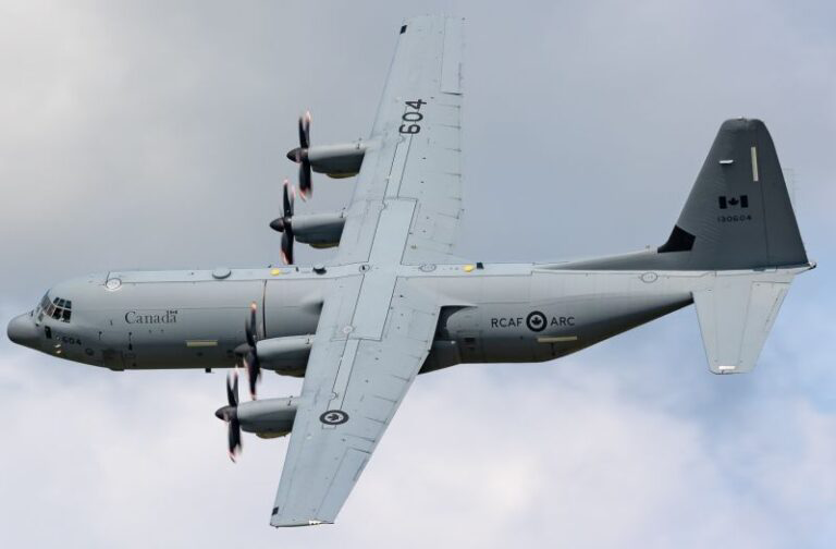 Royal Canadian Air Force plane mid-flight against a cloudy sky.