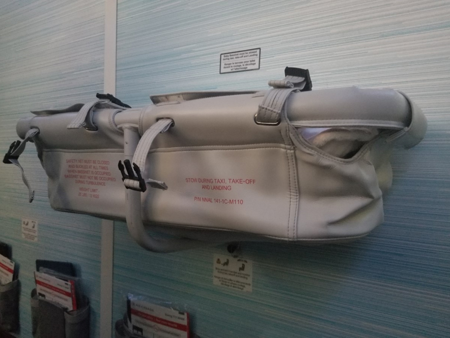 a white and grey Aviation Safety Systems Baby Bassinet installed on a wall