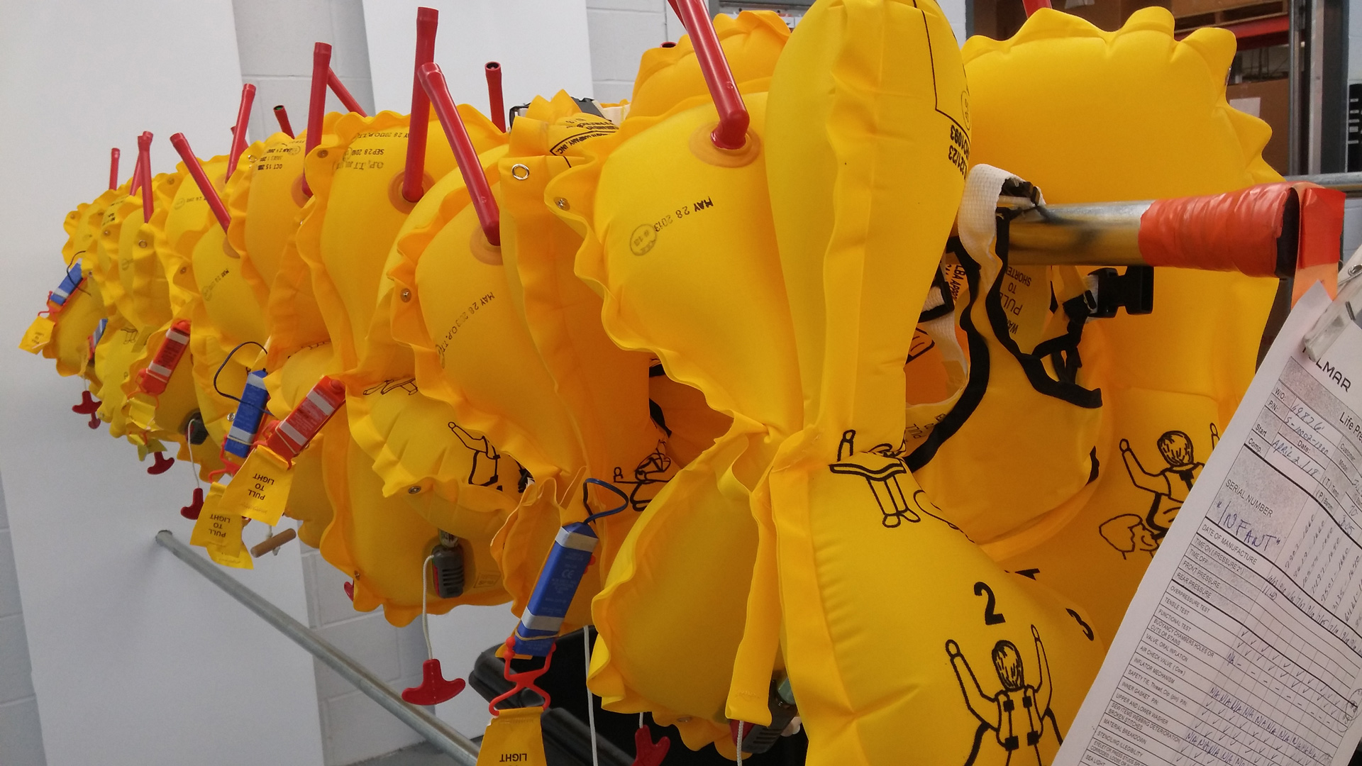 Row of inflated yellow life jackets hanging on a rack.