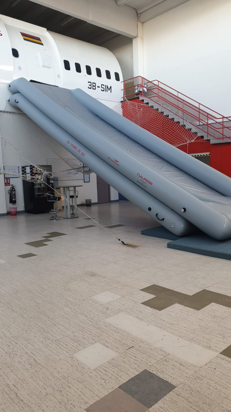 An aircraft emergency slide deployed inside a training facility.